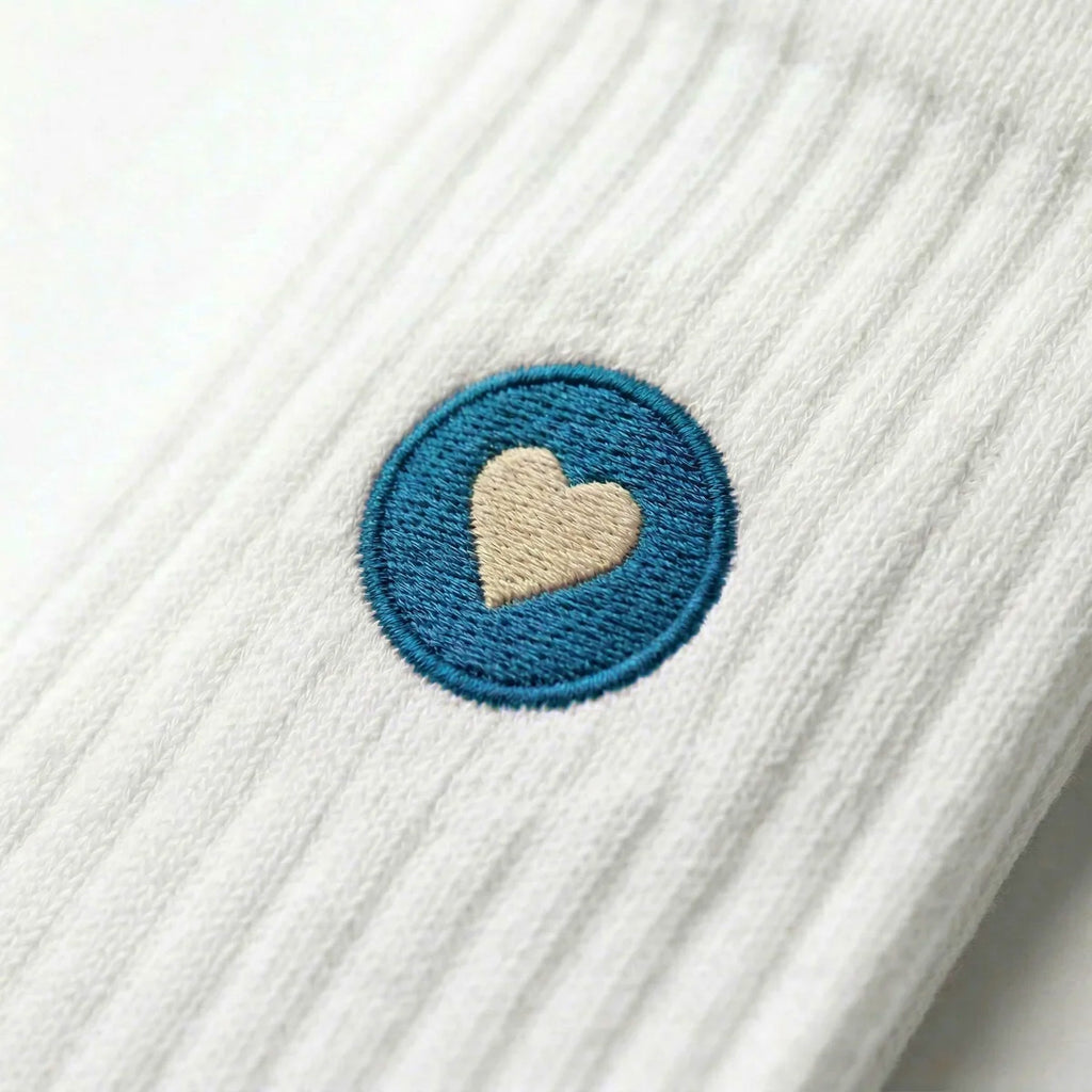 Detailaufnahme einer weissen Premium Socken aus Bio-Baumwolle mit blauem Herzlogo vor weissem Hintergrund.
