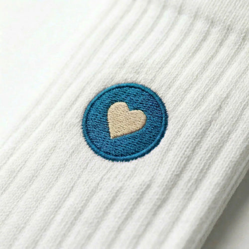 Detailaufnahme einer weissen Premium Socken aus Bio-Baumwolle mit blauem Herzlogo vor weissem Hintergrund.
