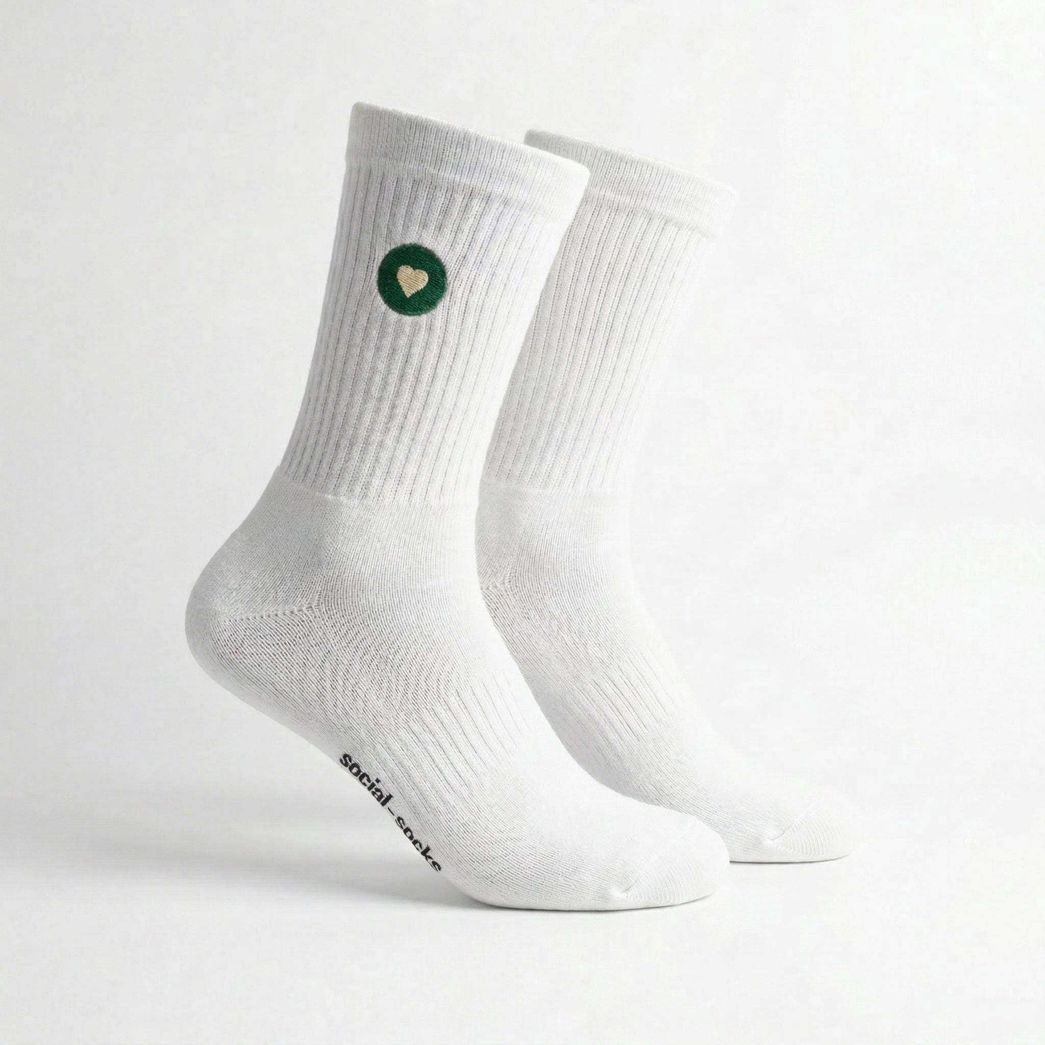 Weisse Premium Socken aus Bio-Baumwolle mit grünem Herzlogo vor weissem Hintergrund.